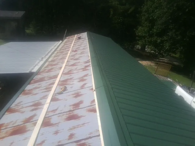 Old rusted panels beside newly installed green metal roofing — Wind Damage Roof Repair by Roofing Brothers in Fort Riley