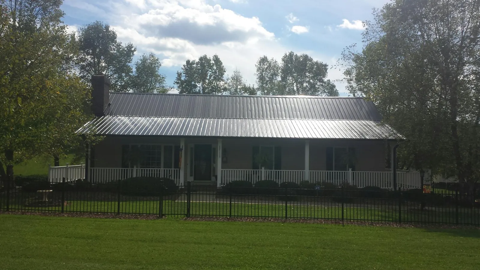 Gray metal roof on a brick ranch with a full width front porch — Gutter Guard Installation work by our crew in Fort Riley