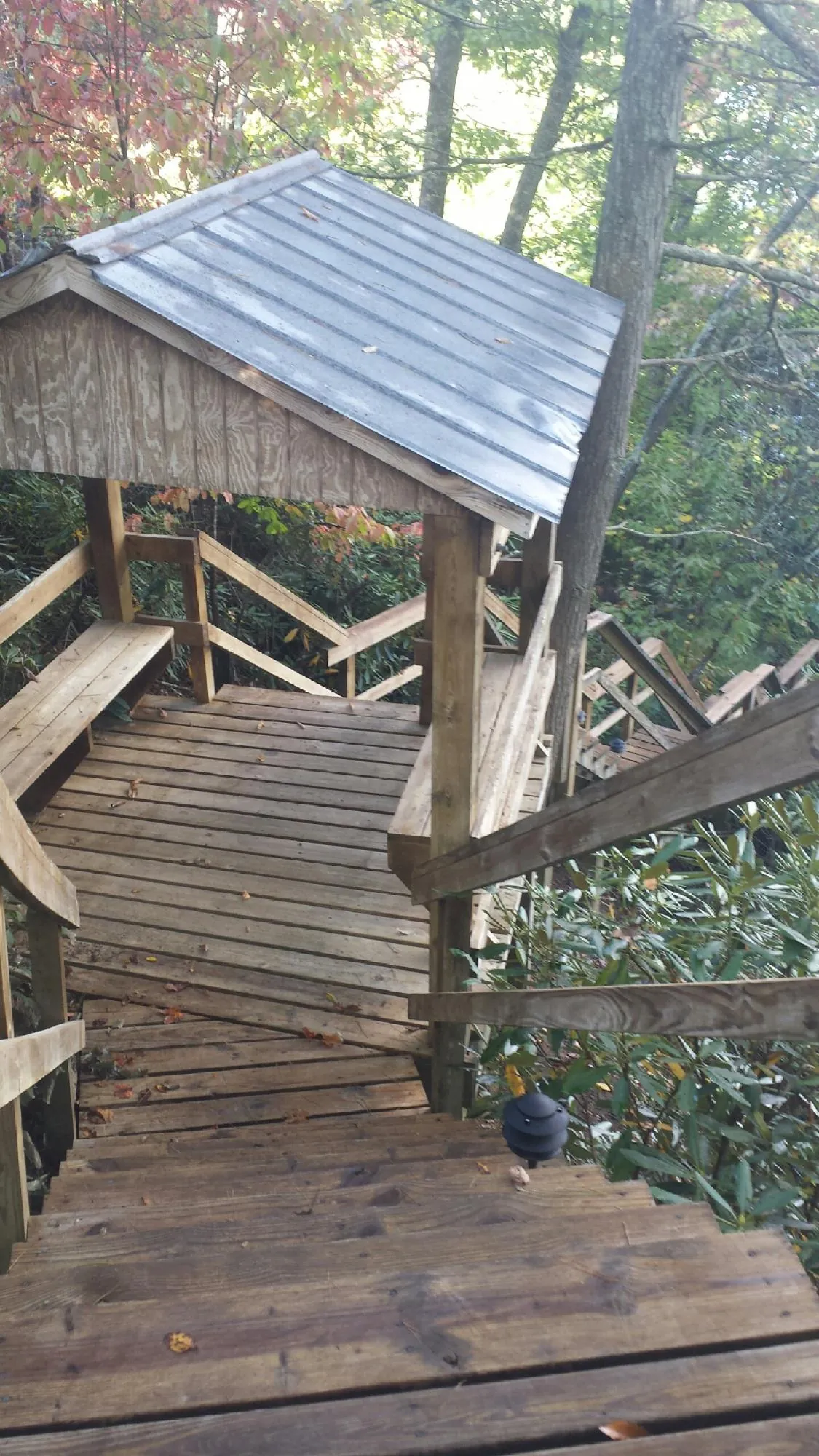 Metal roofed shelter over wooden steps on a wooded walkway — Skylight Repair & Installation work by our crew in Fort Riley