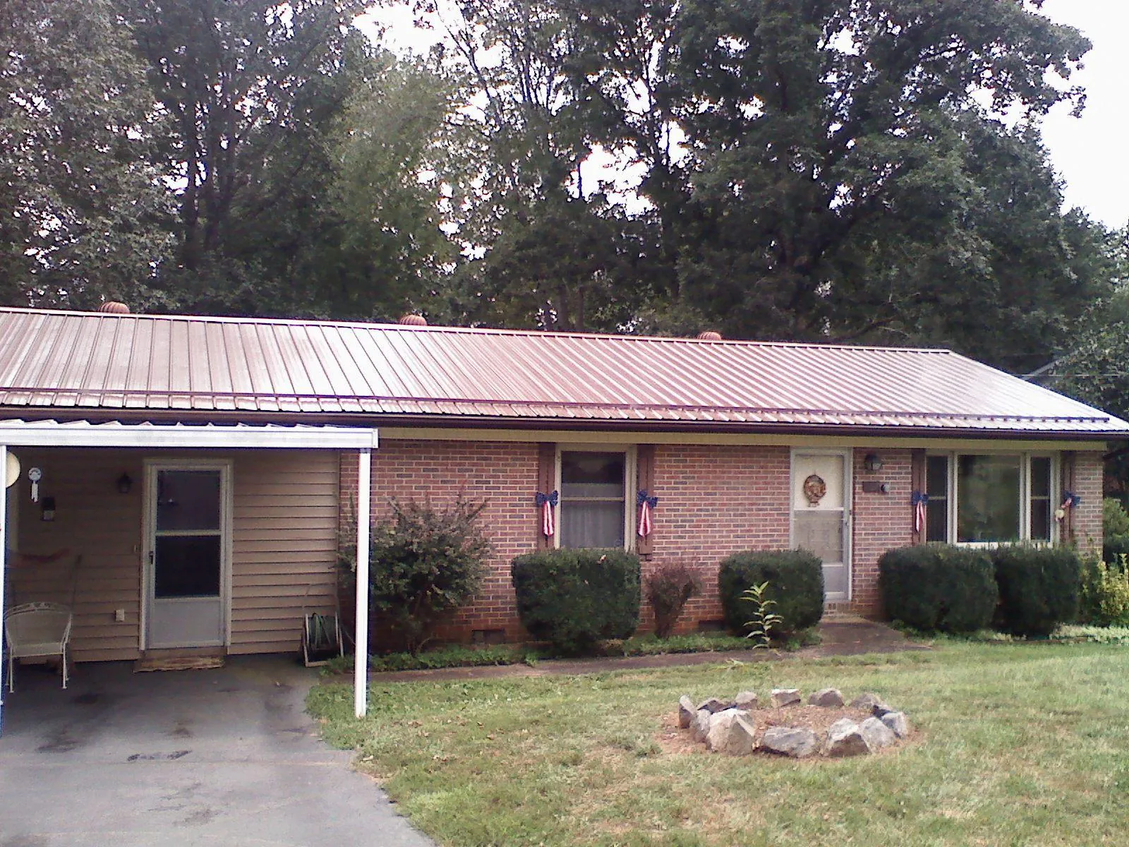 Bronze metal roof and carport on a brick ranch home — Roof Repair work by our crew in Fort Riley