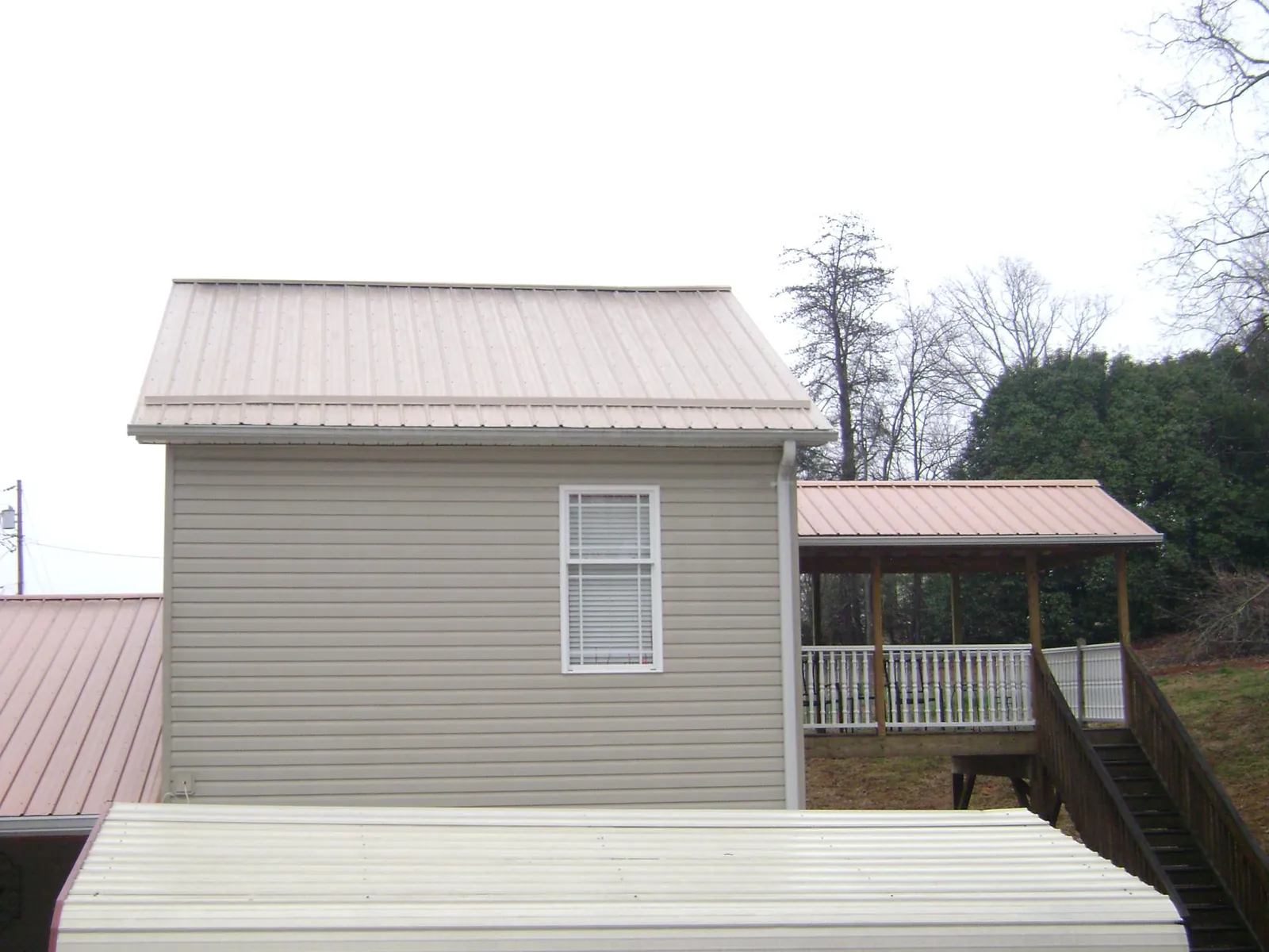 Tan metal roofs on a two story addition and attached porch, from a Roof Replacement job in Fort Riley