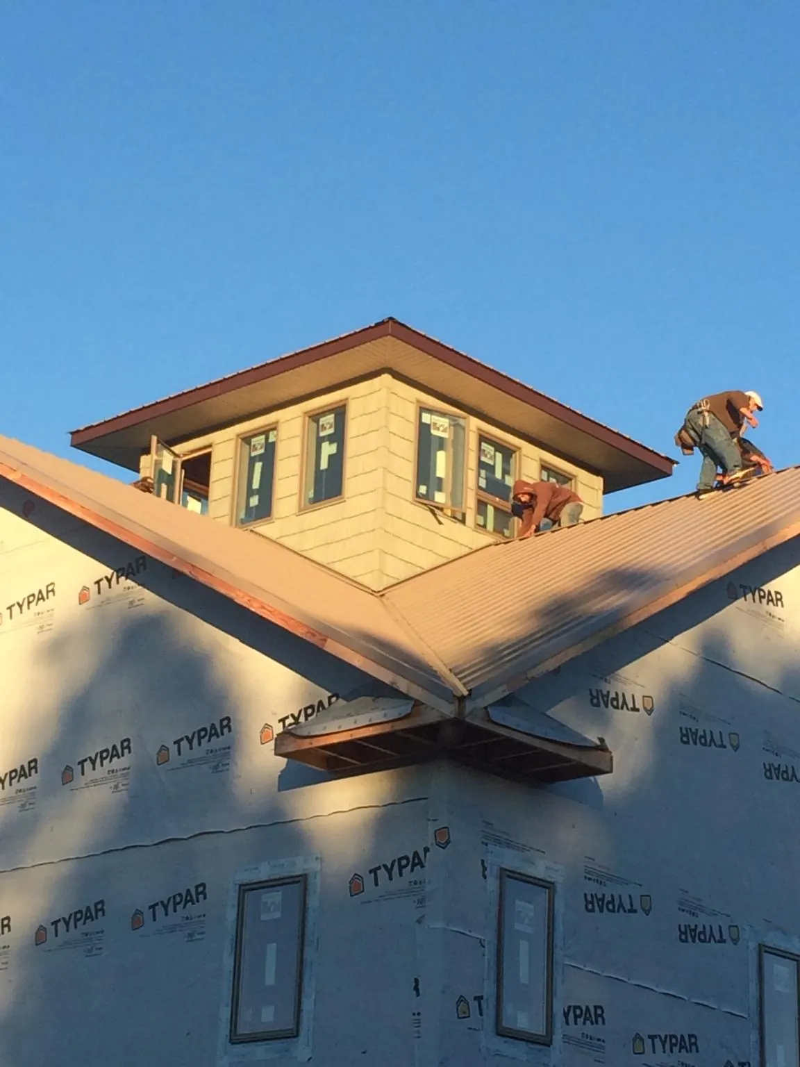 Roofers working around a rooftop cupola on a new metal roof at sunset — Roof Waterproofing in Fort Riley by Roofing Brothers